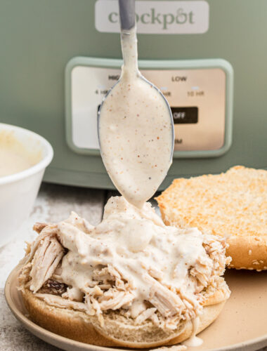 Alabama sauce being poured over a chicken sandwich.