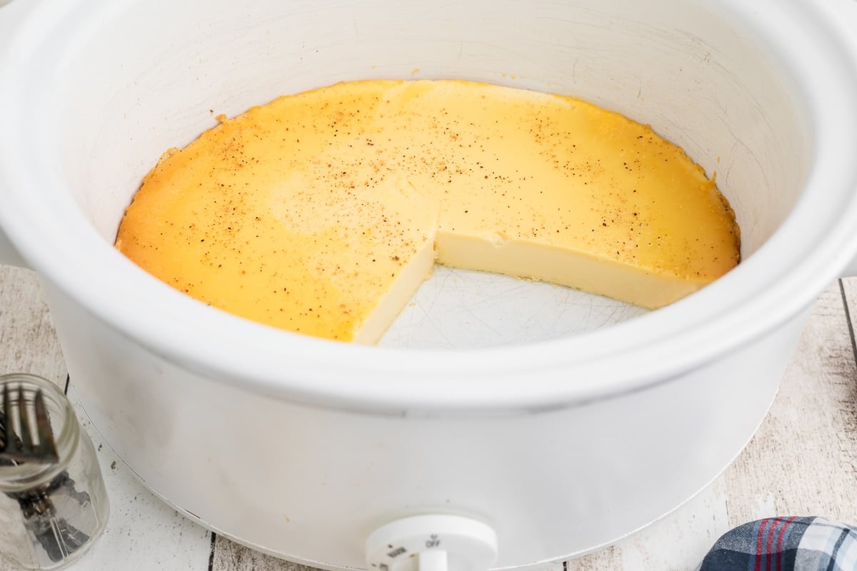 baked custard in crockpot with a slice out of it.