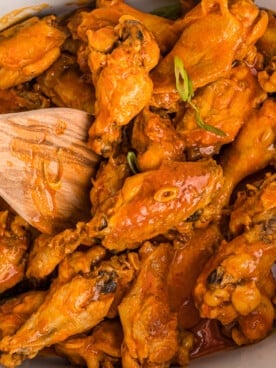 Spoon in buffalo wings in a crockpot.