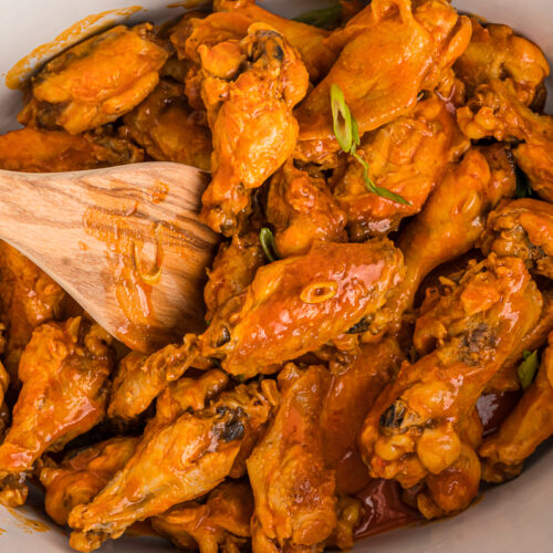 Spoon in buffalo wings in a crockpot.