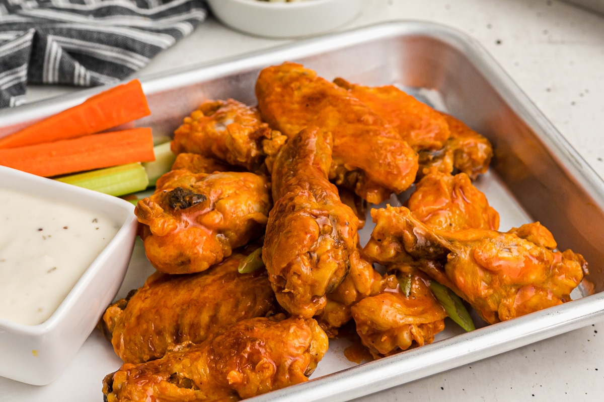buffalo wings on a sheet pan with ranch and vegetables.