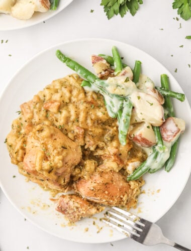 Cooked chicken, stuffing, green beans on a white plate.