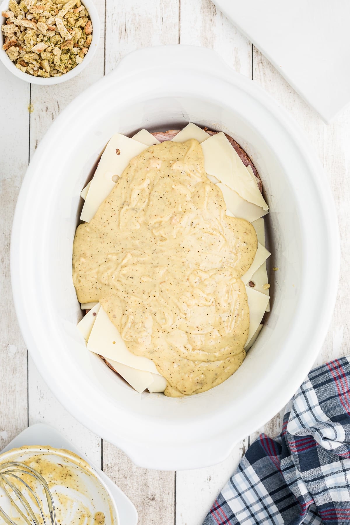 Cream of chicken soup on top of swiss cheese, ham and chicken in a slow cooker.