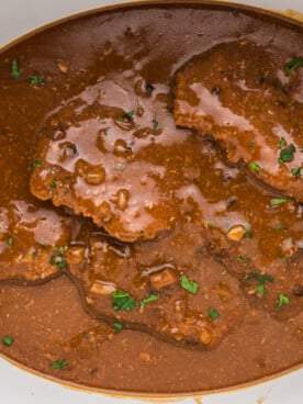Cube steak in slow cooker with parsley on top.