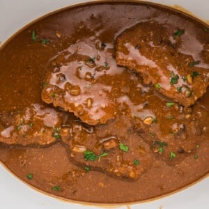 Cube steak in slow cooker with parsley on top.