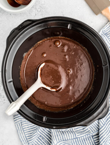 Hot fudge in a slow cooker with spoon in it.