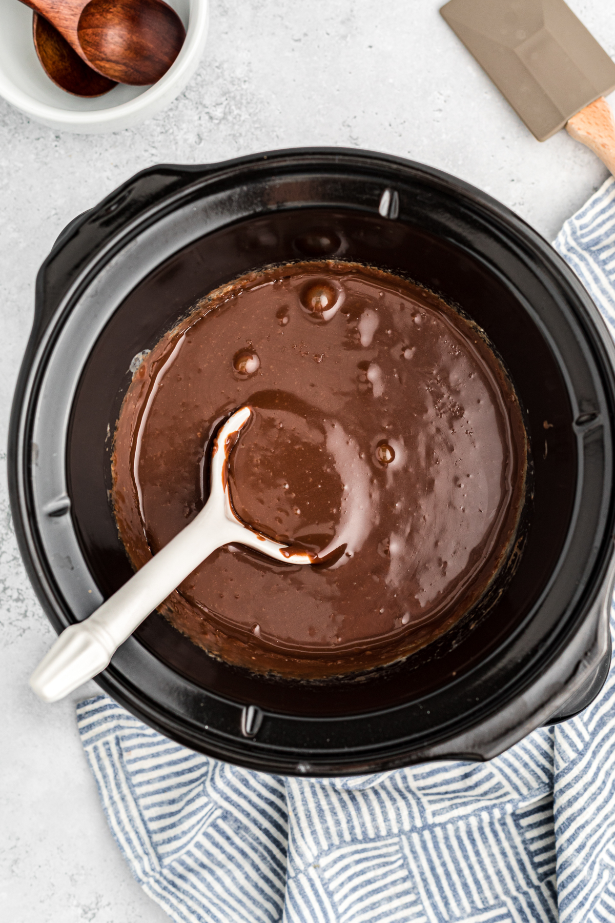 Hot fudge in a slow cooker with spoon in it.