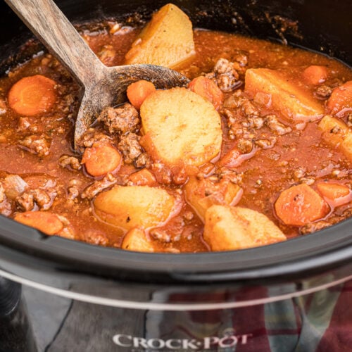 Side view of poor man's stew in crockpot with wooden spoon in it.