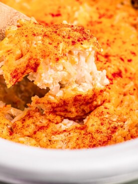 Cooked potatoes romanoff on a spoon.