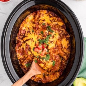 spoon in vegetarian enchilada casserole in slow cooker.