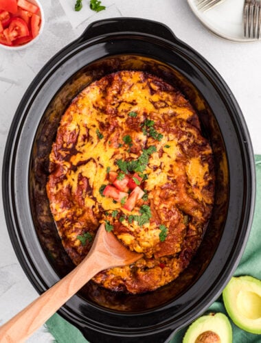 spoon in vegetarian enchilada casserole in slow cooker.