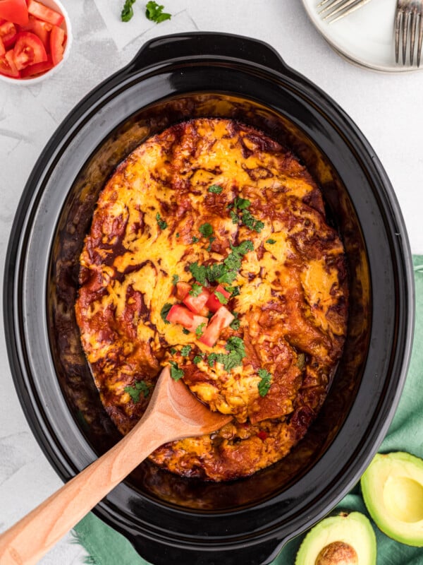 spoon in vegetarian enchilada casserole in slow cooker.