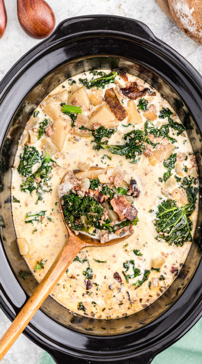 long image of zuppa toscana with wooden spoon in it.