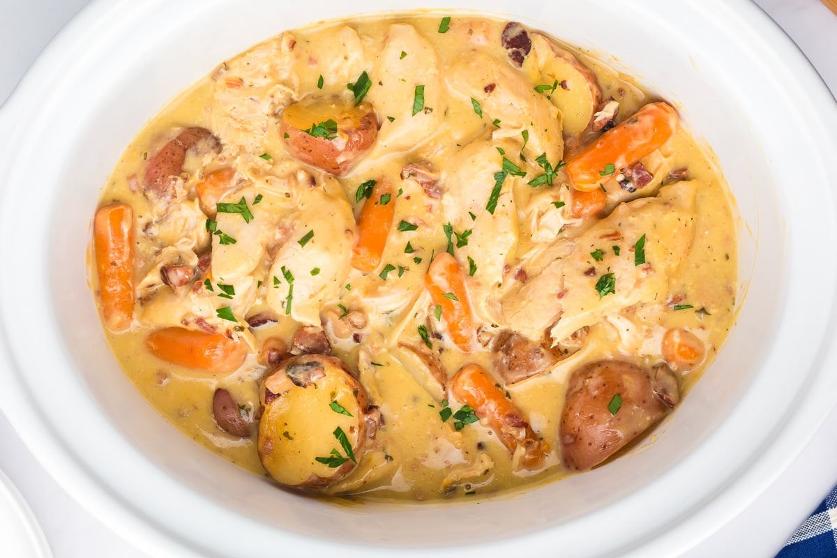 Overhead shot of cooked bacon ranch chicken and vegetables in a slow cooker.