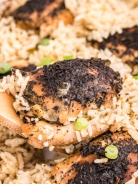 close up of basil chicken and rice on a wooden spoon.