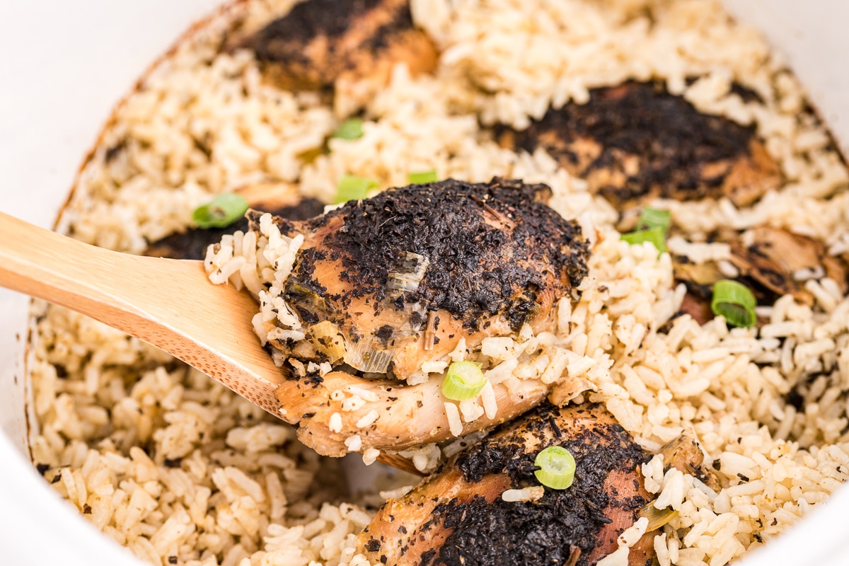 close up of basil chicken and rice on a wooden spoon.