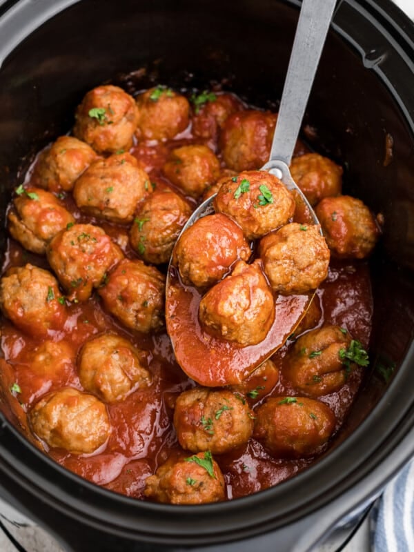 Beer meatballs on a spoon in a crockpot.