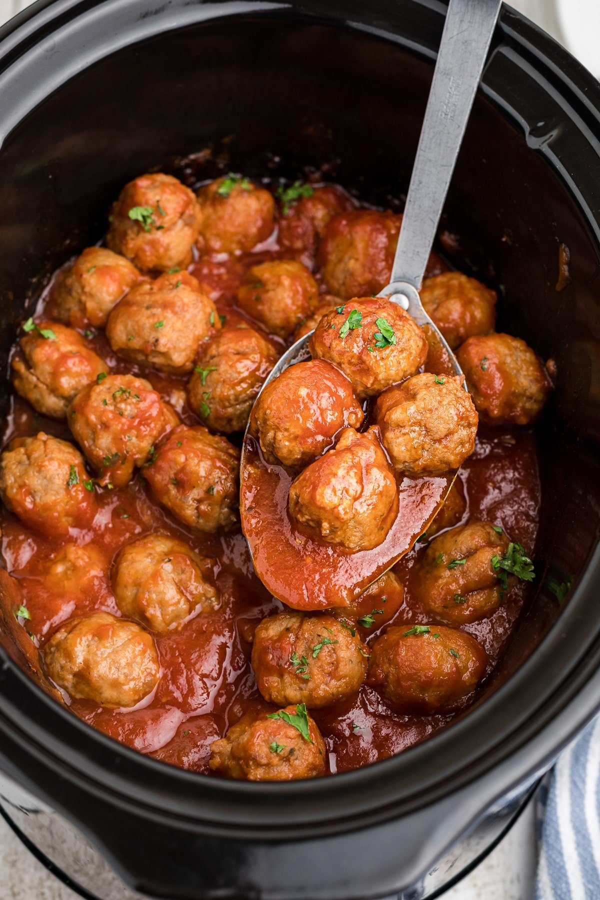 Beer meatballs on a spoon in a crockpot.