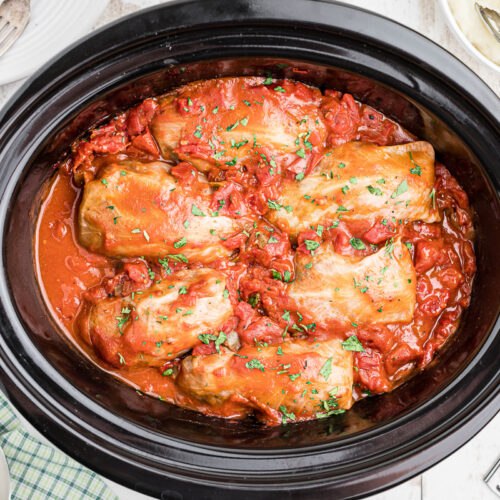 cooked cabbag rolls in red sauce in a slow cooker.