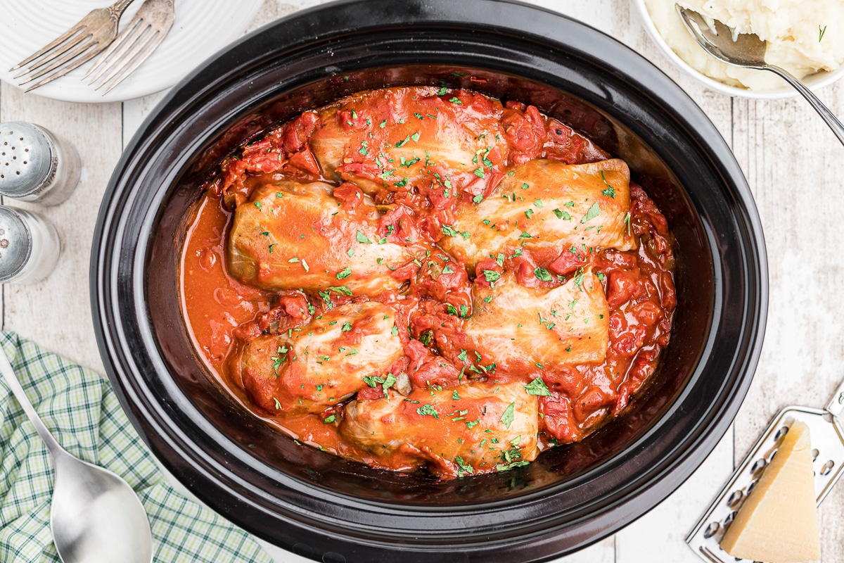 cooked cabbag rolls in red sauce in a slow cooker.