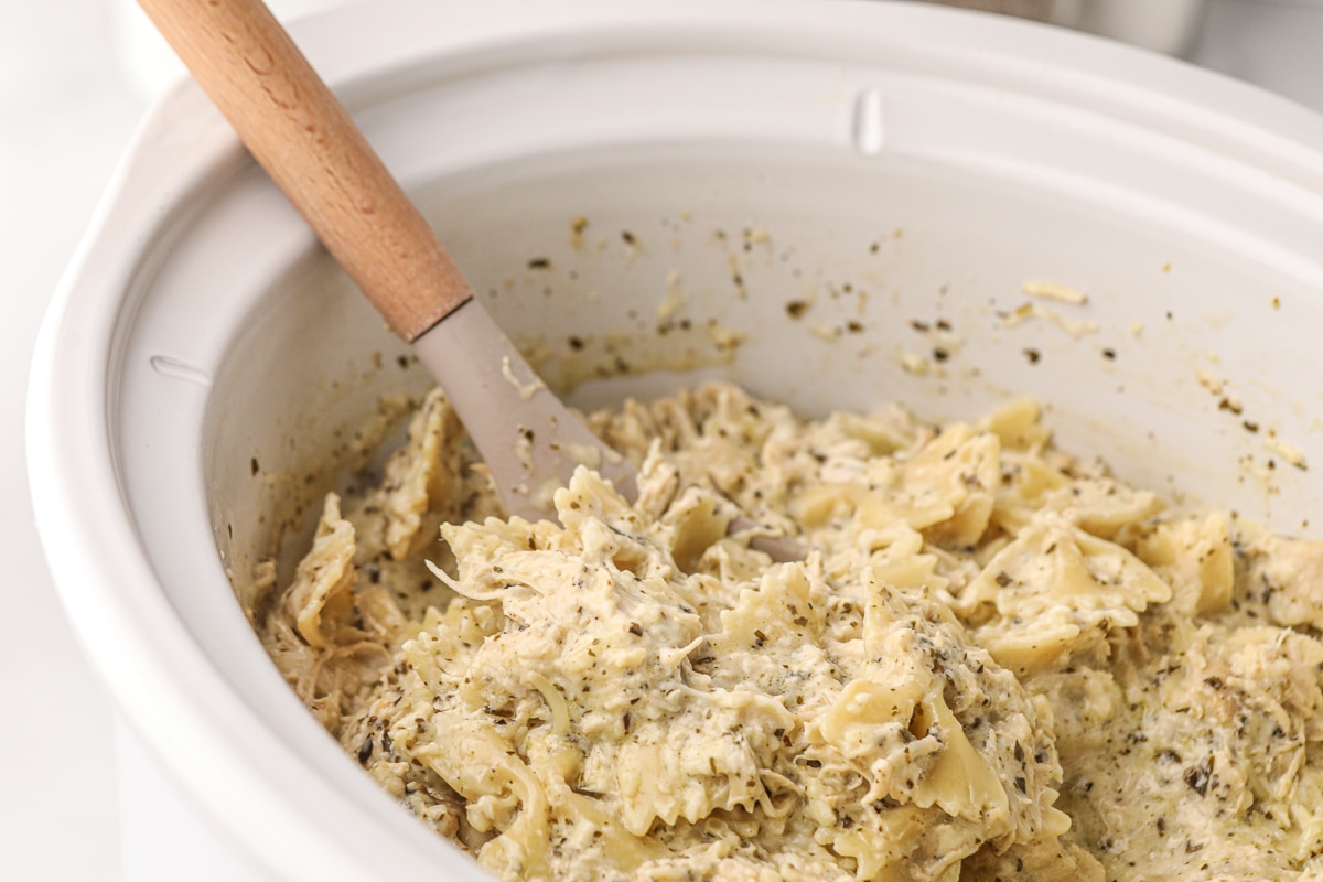 side view of creamy pesto chicken pasta with spoon in it.