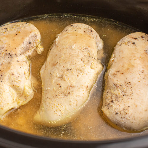 close up of chicken breasts in a slow cooker.