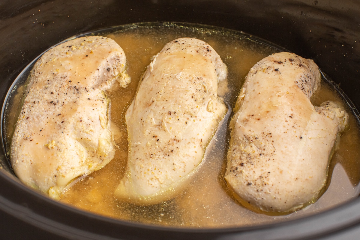 close up of chicken breasts in a slow cooker.