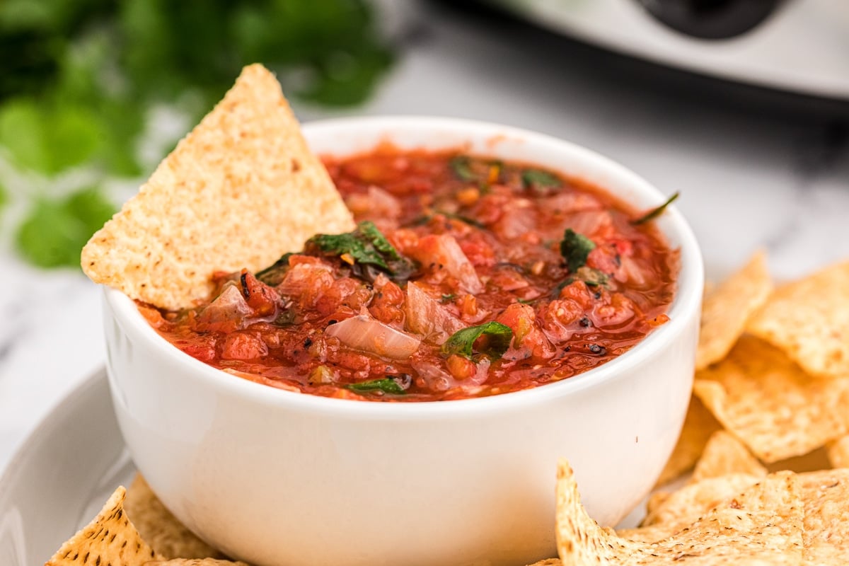 Cooked salsa in a bowl with a chip in it.