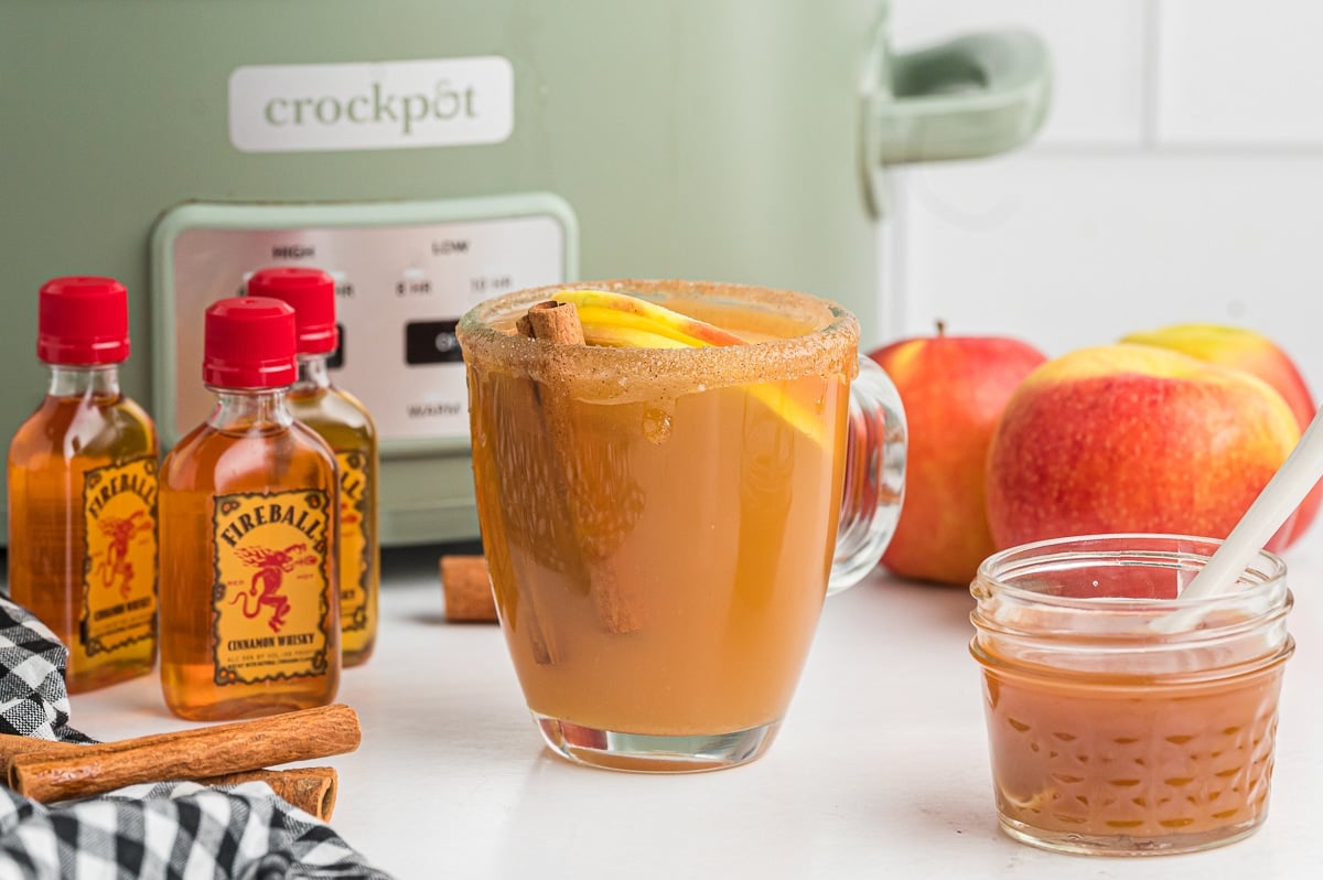 Mug of cider with mini bottles of fireball next to them.