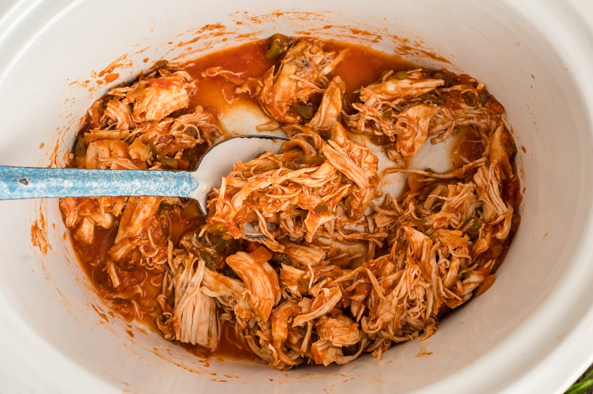 salsa chicken in a crockpot with spoon in it.