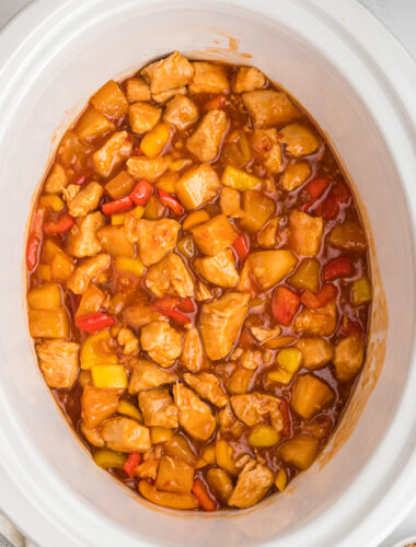 Cooked sweet and sour chicken in a white slow cooker.