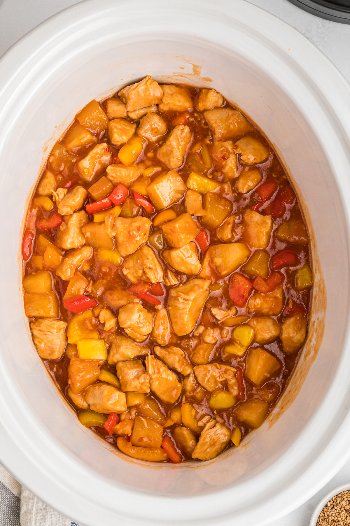 Cooked sweet and sour chicken in a white slow cooker.