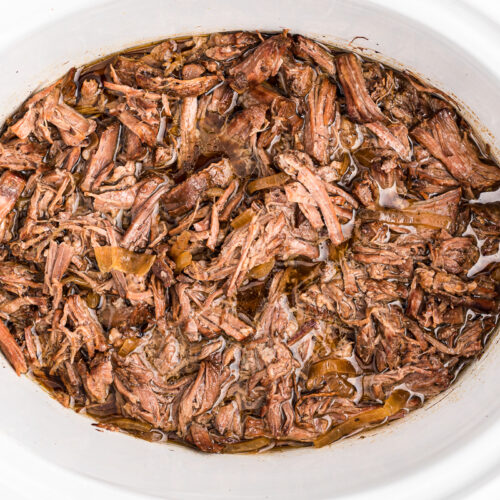 close up images of shredded pot roast in a slow cooker.