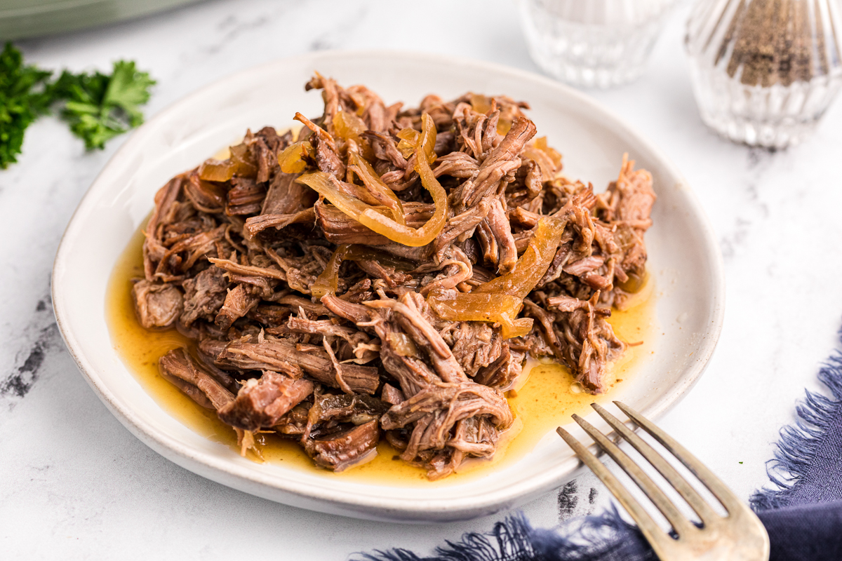 Plate of pot roast with onions on top.