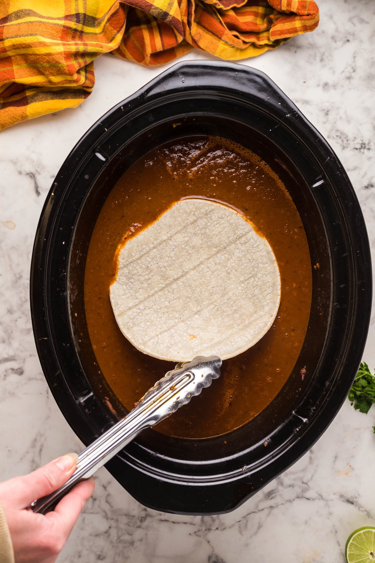 Tortilla being dipped into birria consumme .
