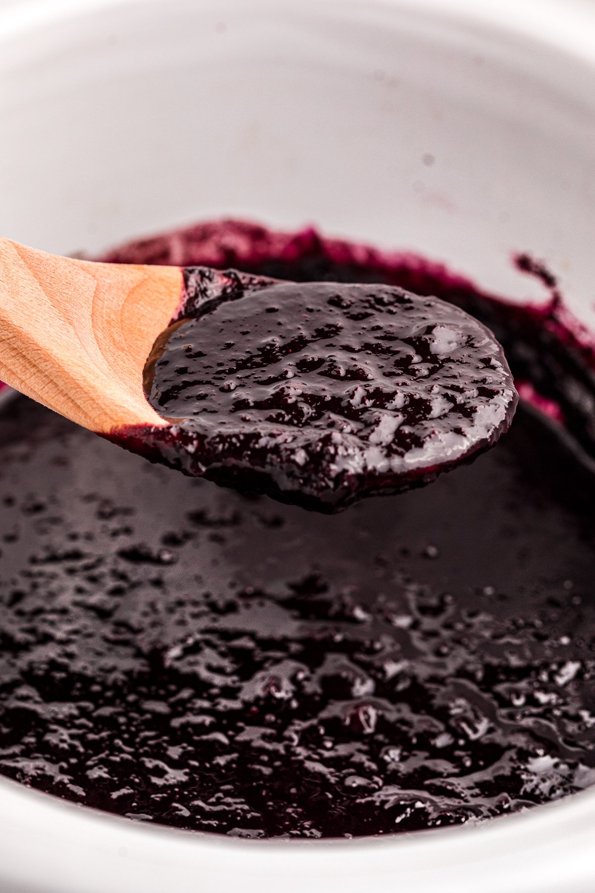 Blueberry butter on a spoon coming from a slow cooker.