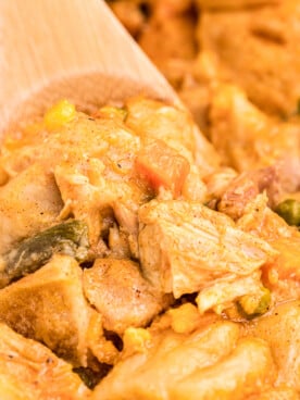 close up of chicken bubble up casserole with wooden spoon in it.