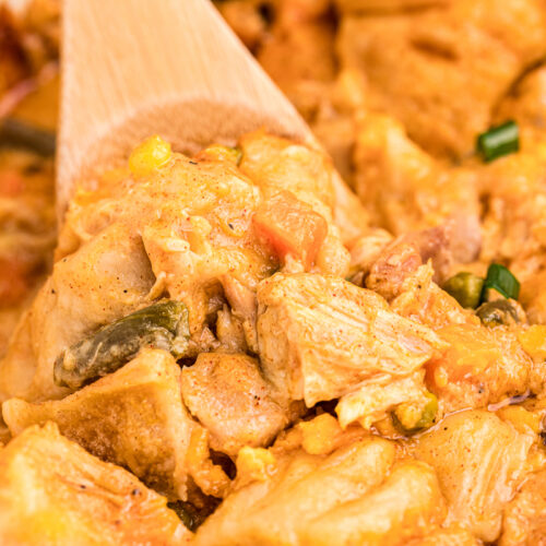 close up of chicken bubble up casserole with wooden spoon in it.
