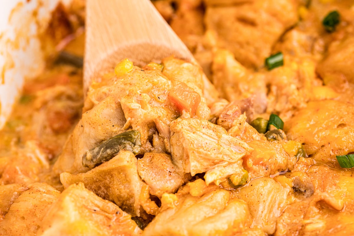 close up of chicken bubble up casserole with wooden spoon in it.