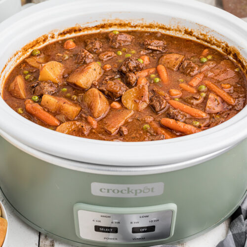 Done cooking beef stew in a green slow cooker.