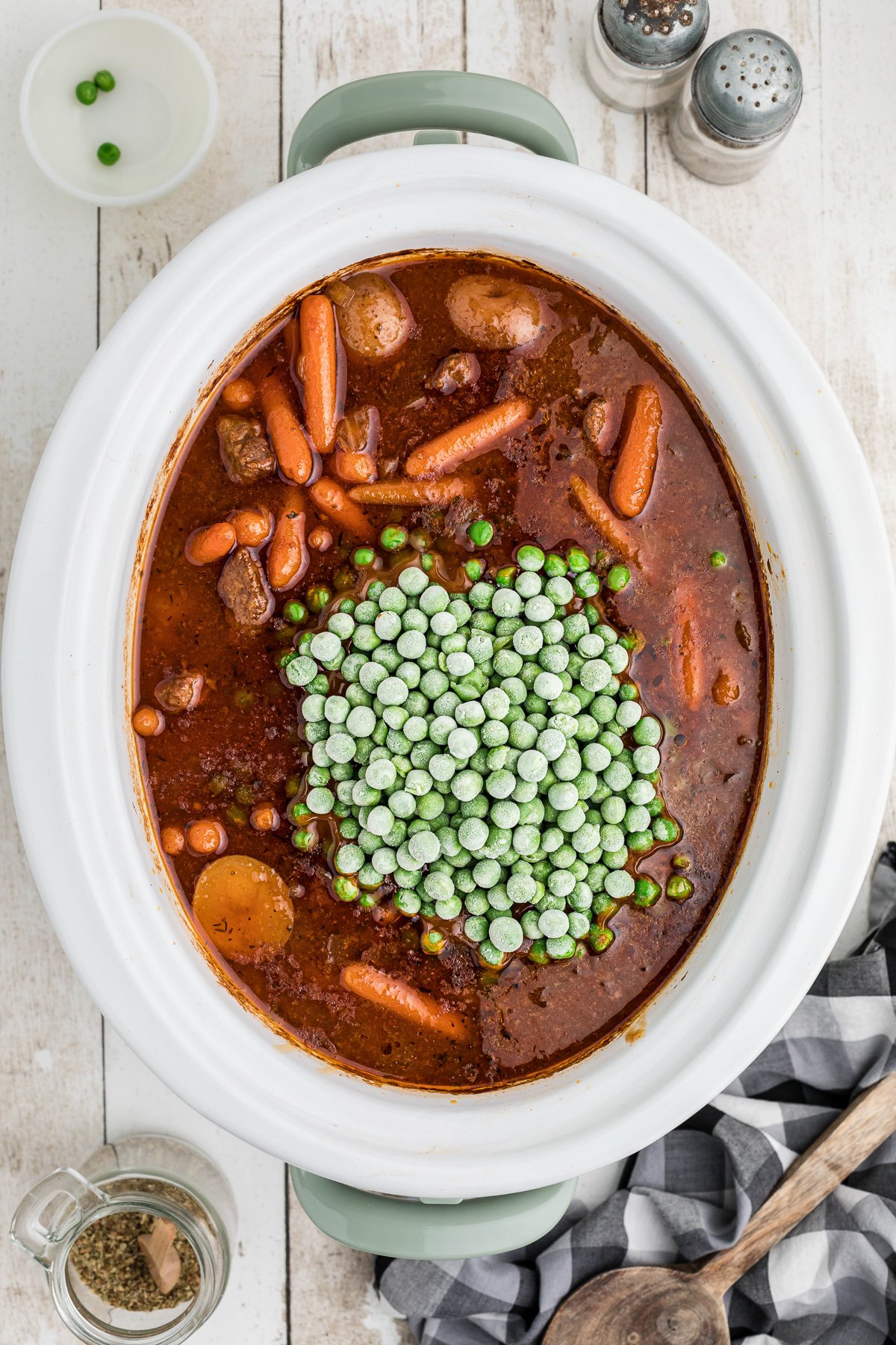 Cooked beef stew meat with peas on top.