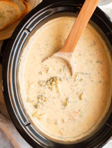 broccoli cheese soup in the slow cooker with a wooden spoon.