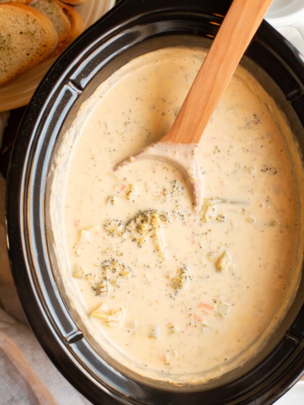 broccoli cheese soup in the slow cooker with a wooden spoon.