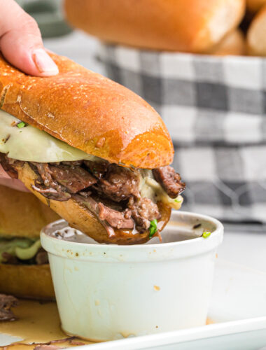 french dip sandwich being dipped in au jus.