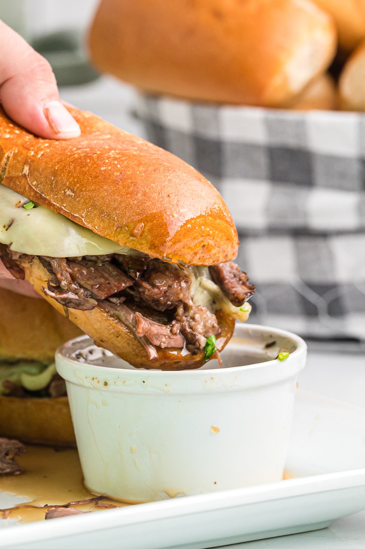 french dip sandwich being dipped in au jus.