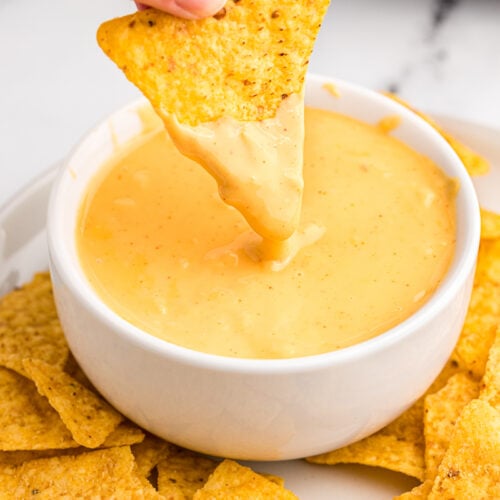 A chip being dipped into cheese sauce.