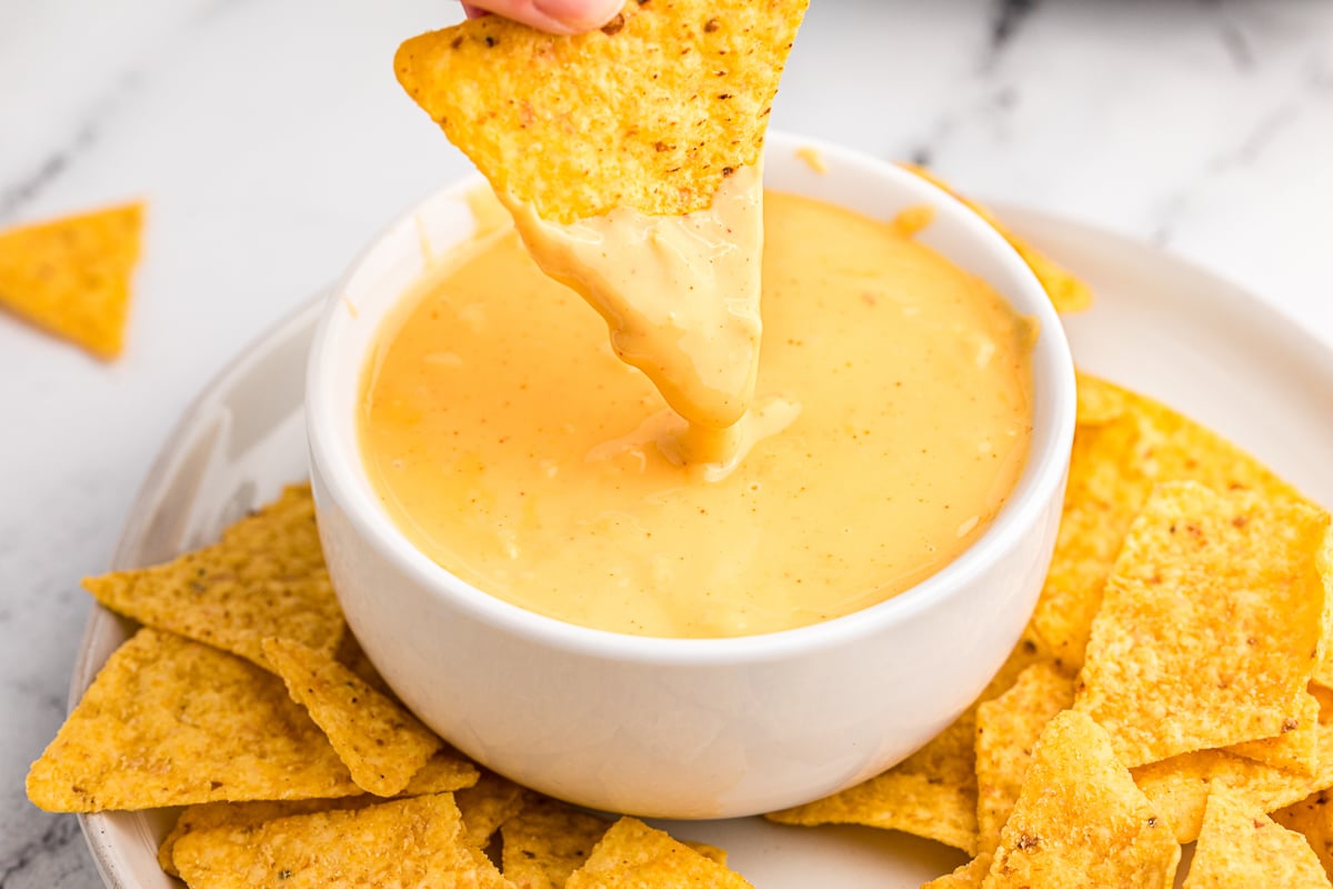 A chip being dipped into cheese sauce.