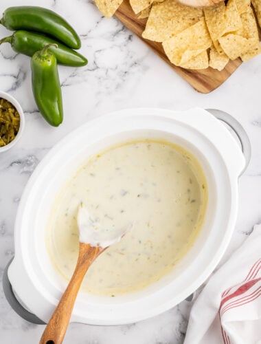 queso blanco in a slow cooker with chips on the side.