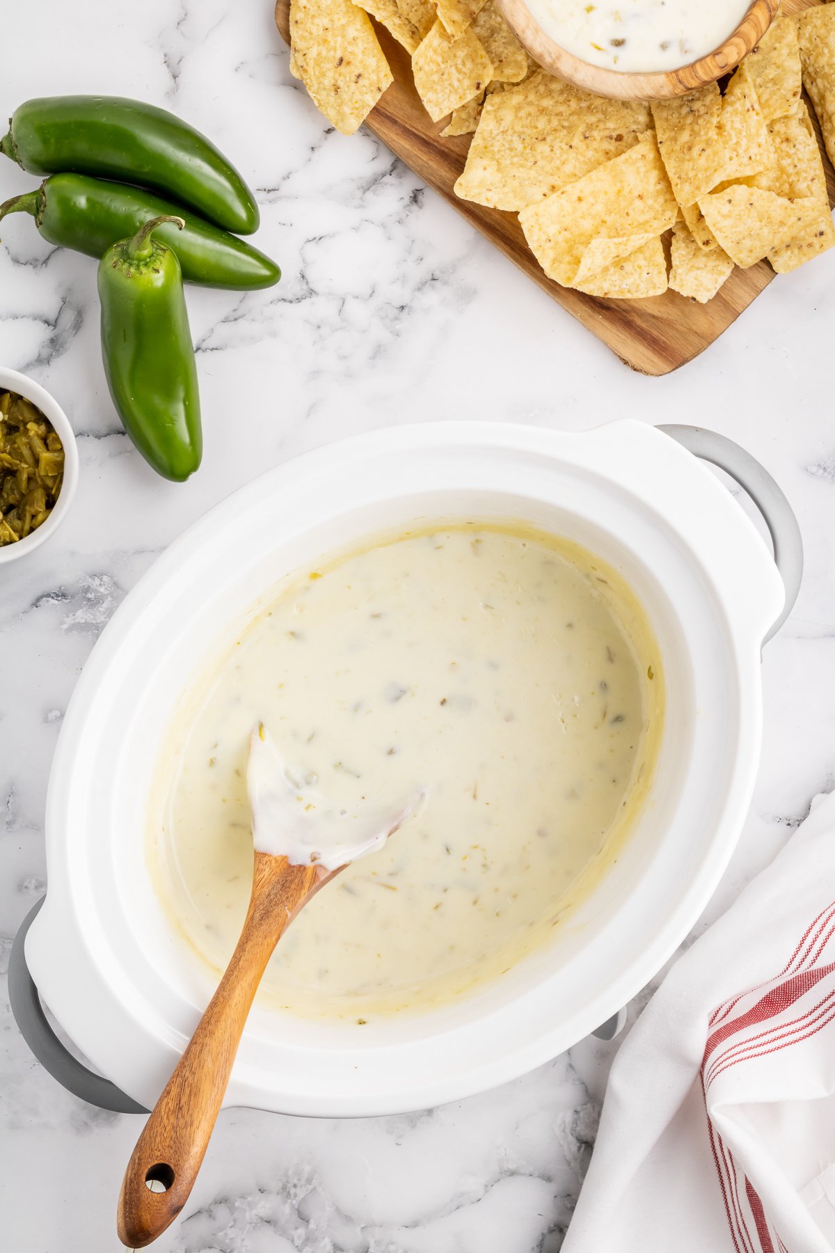 queso blanco in a slow cooker with chips on the side.