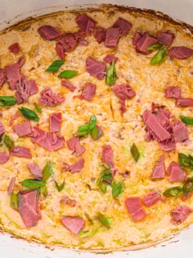 Cooked rueben dip with green onions and corned beef on top.